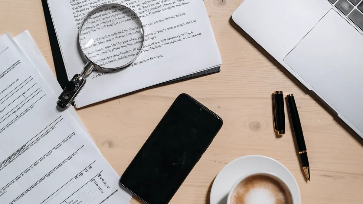 Documents under a magnifying glass next to a laptop